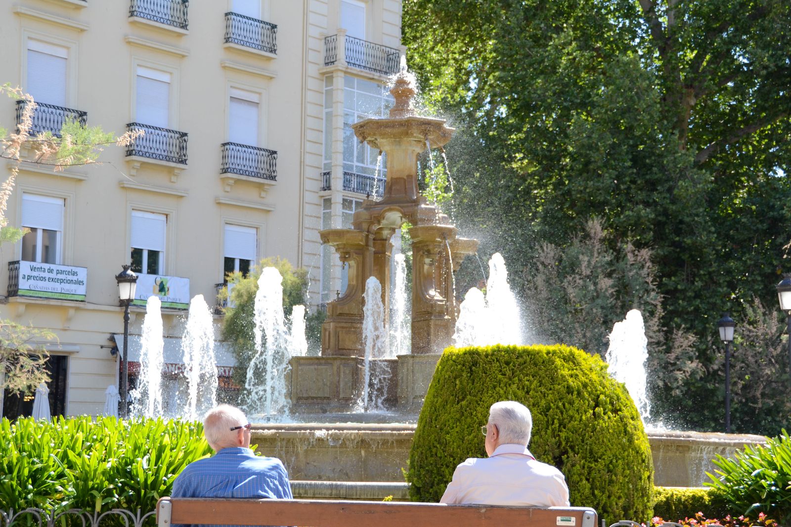 Dos personas frente a la Fuente de las Batallas, en el centro.