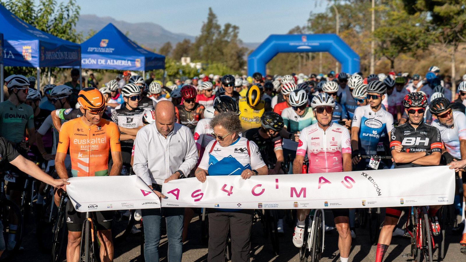 Corte de la cinta de salida antes de dar el pistoletazo de salida a la prueba ciclista.