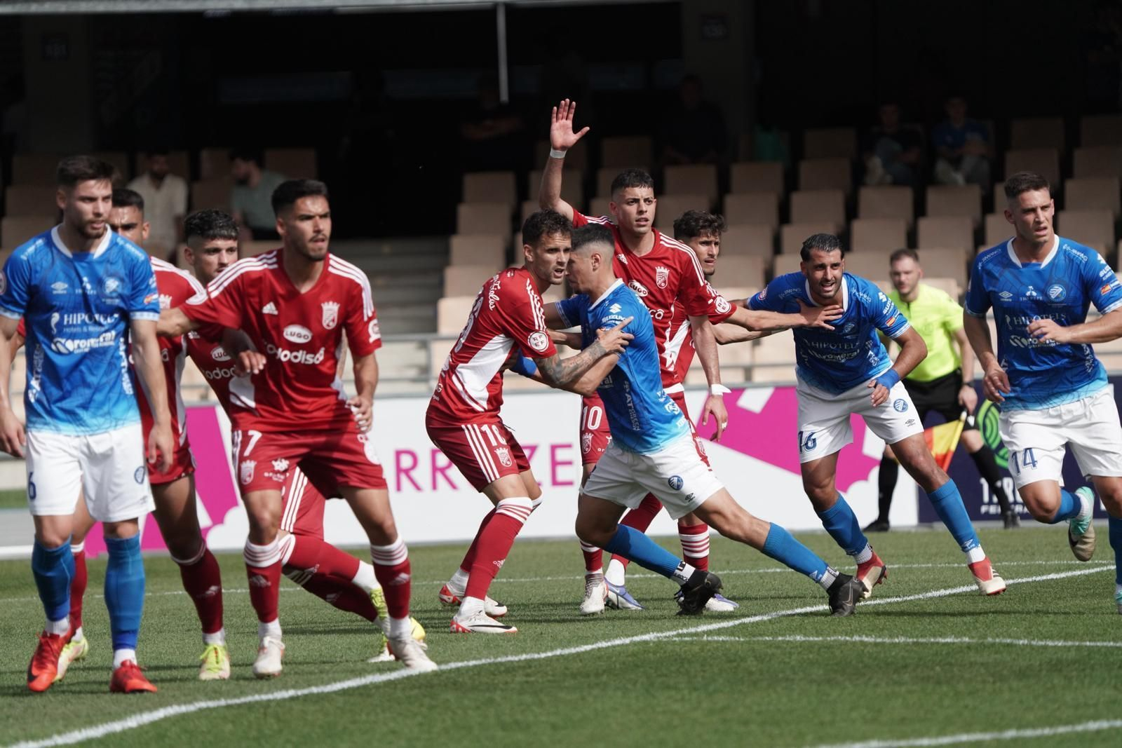Jugadores de uno y otro equipo se agarran en el área en lanzamiento de una falta.