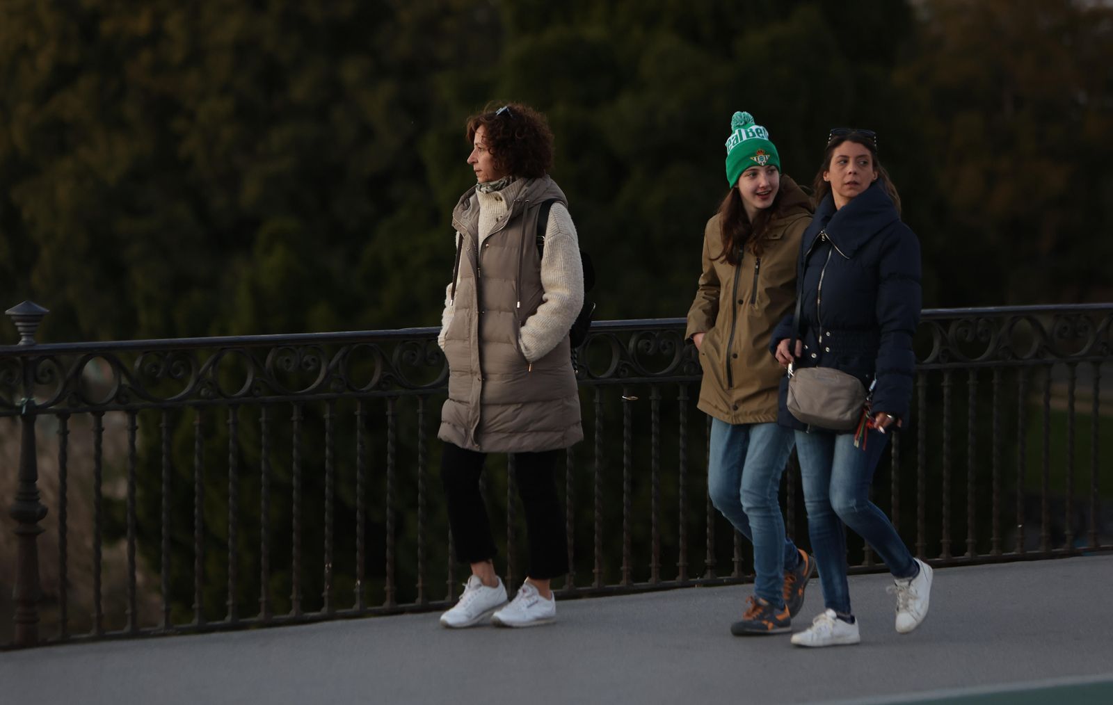 Tres mujeres pasean con ropa de abrigo por el puente de Triana.