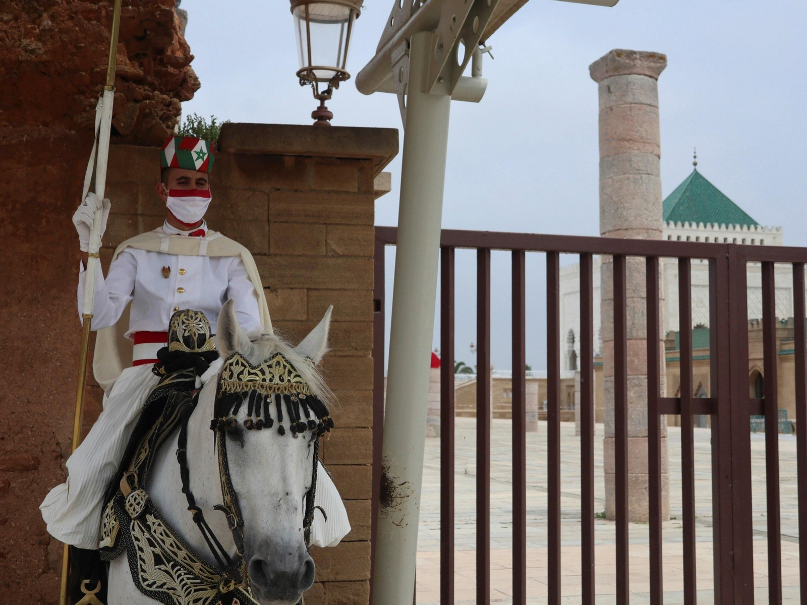 Un miembro de la Guardia Real, protegido con una mascarilla a juego con el uniforme, vigila en el acceso a un monumento en Rabat.