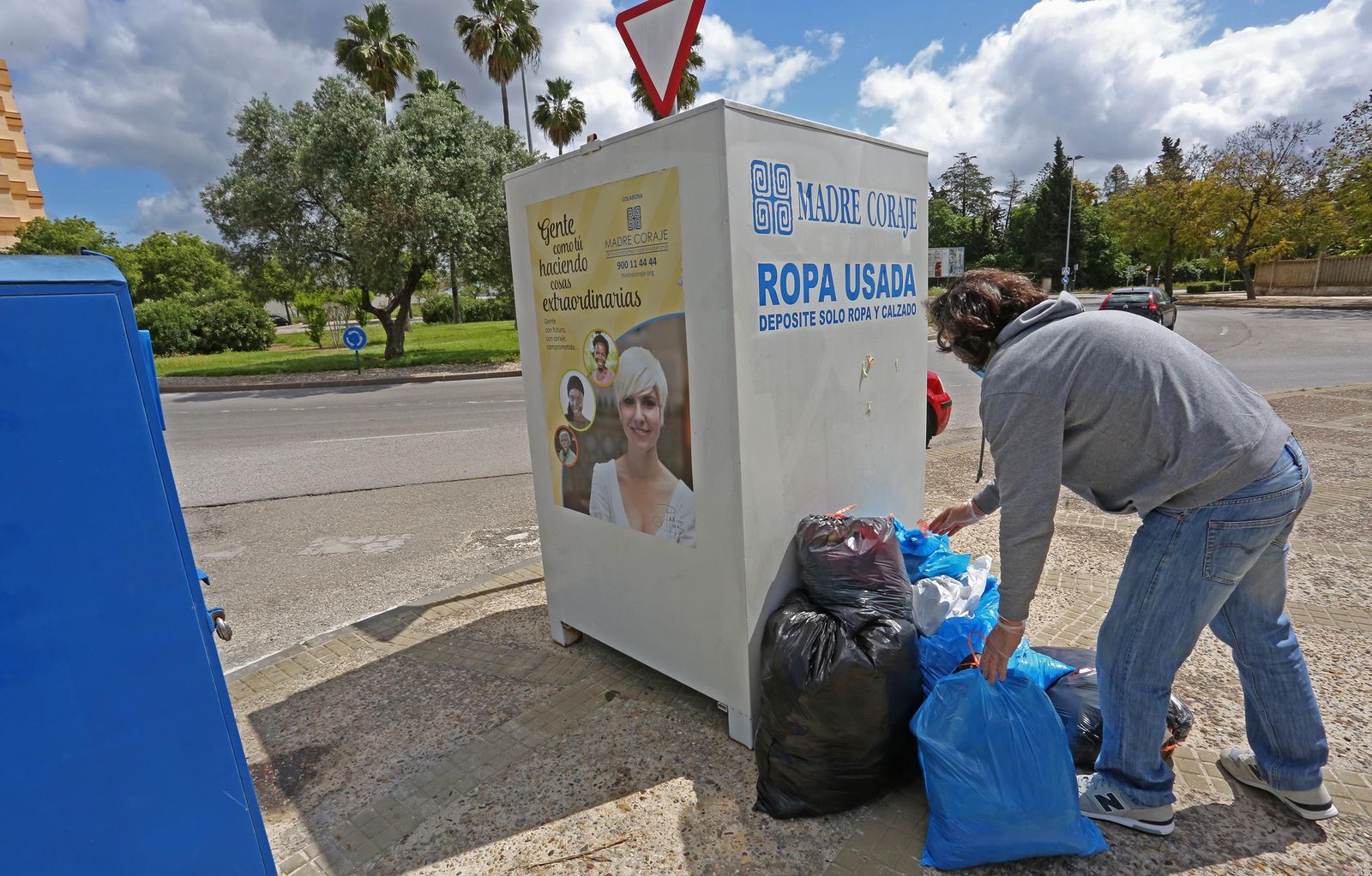 Un hombre deja bolsas junto a un contenedor de Madre Coraje.
