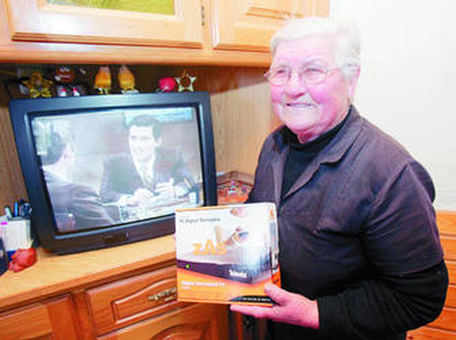 Una anciana muestra su sintonizador de TDT nada más adquirirlo en un supermercado.
