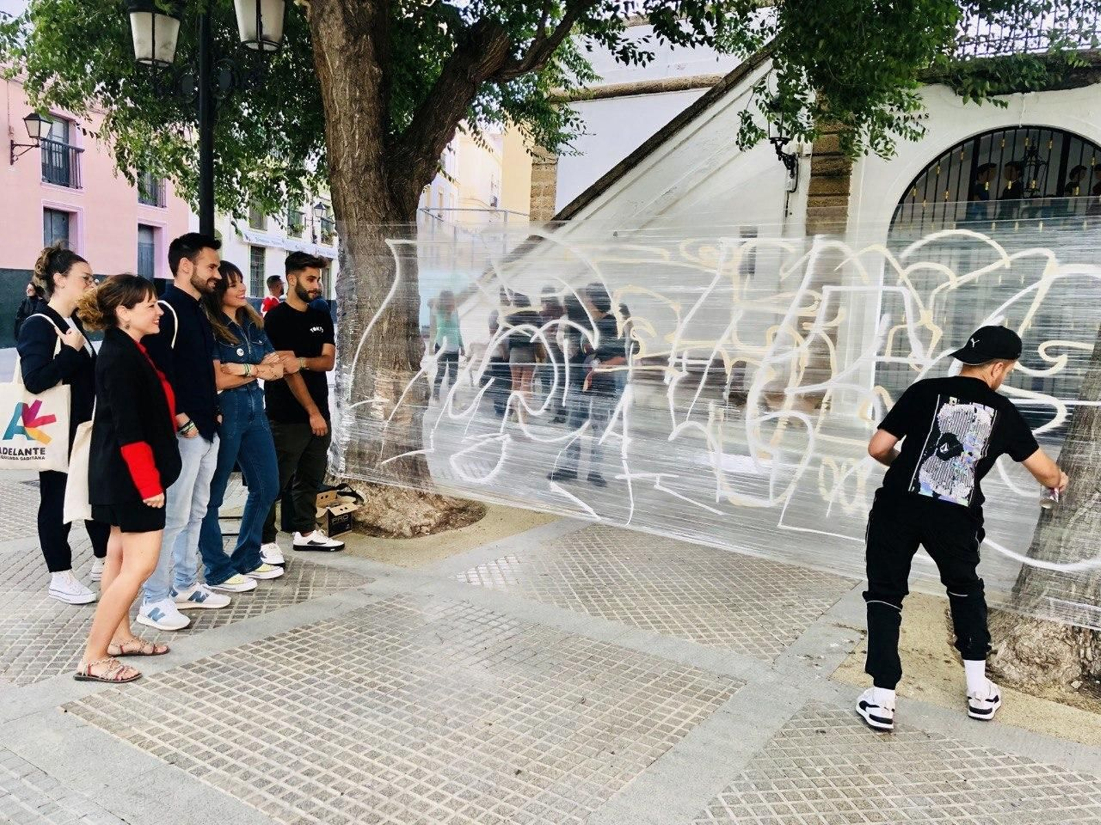 Un joven pinta un grafiti en presencia de los miembros de Adelante Izquierda Gaditana.
