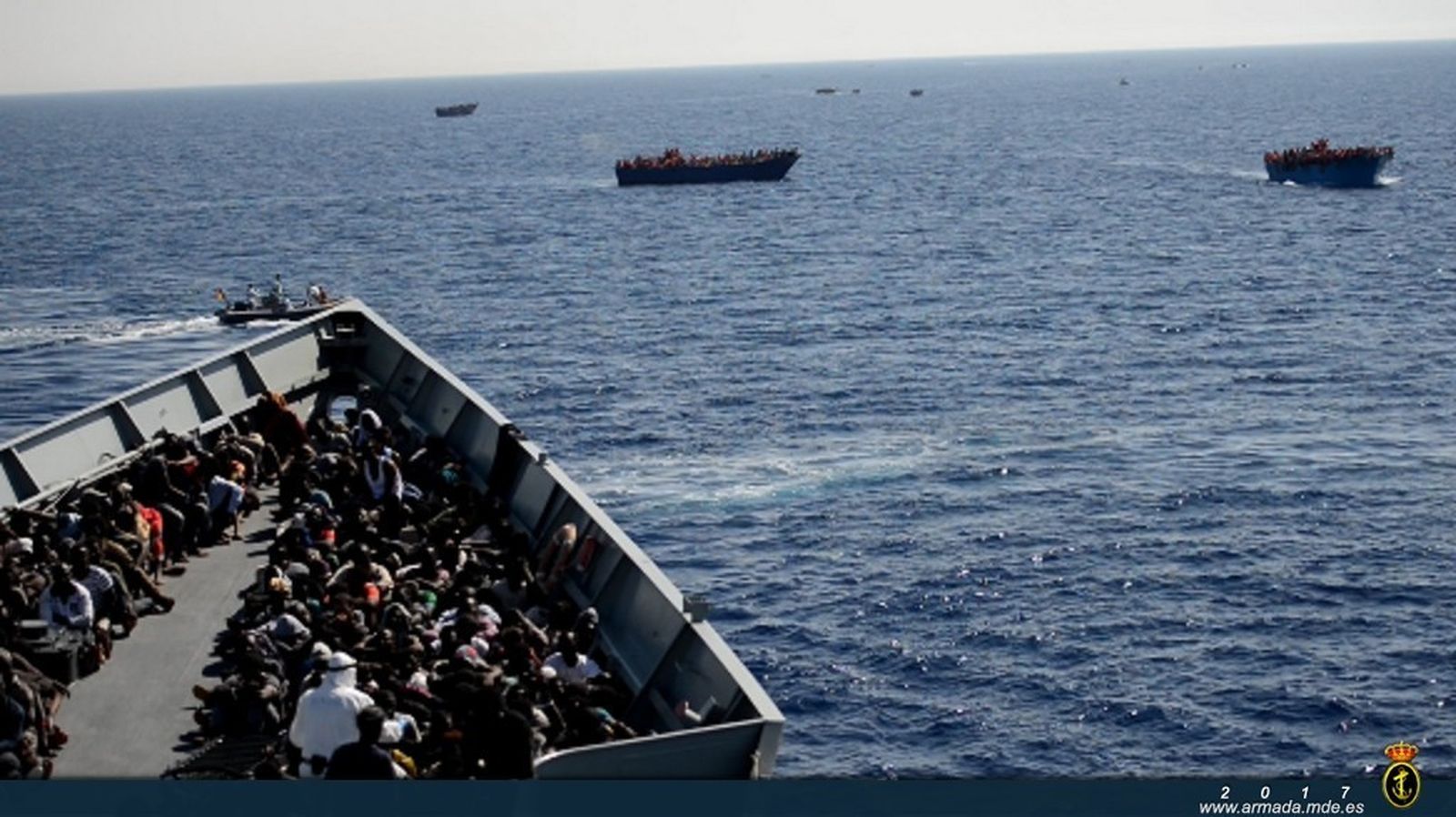 La fragata 'Victoria' durante una operación de rescate con decenas de personas a bordo y otras  embarcaciones a la deriva a su alrededor.