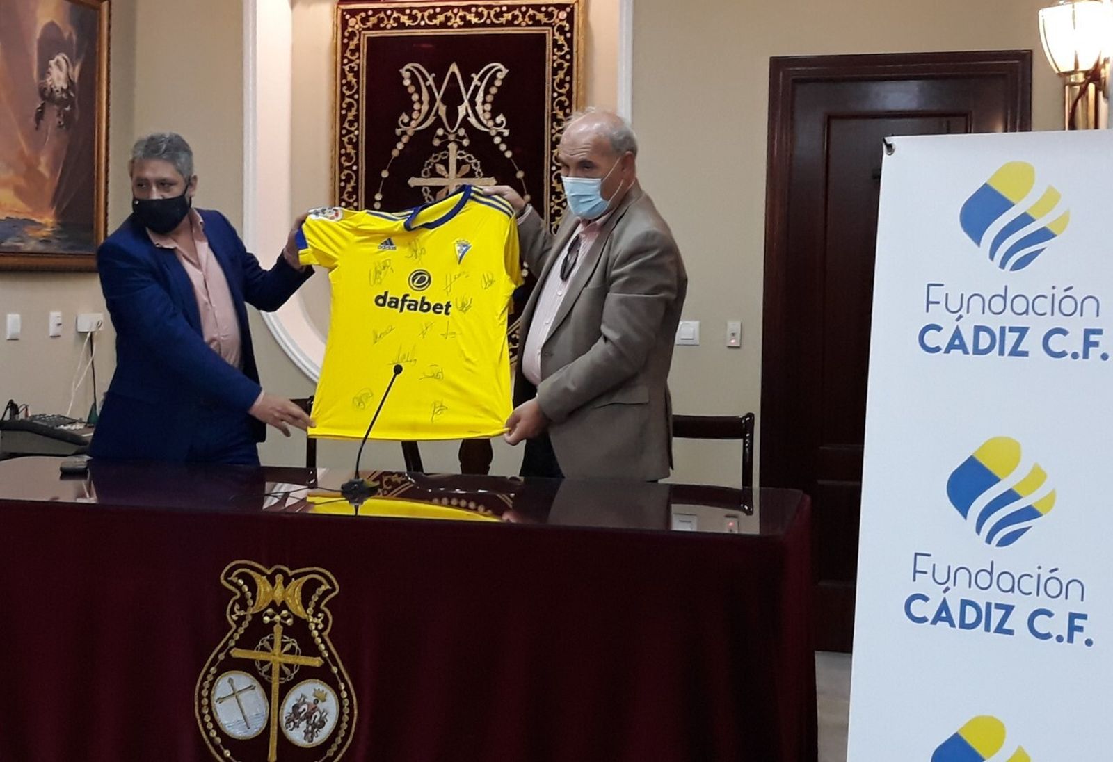 Pepe Mata (i) y Juan Carlos Jurado sostienen la camiseta donada por el club a las cofradías.