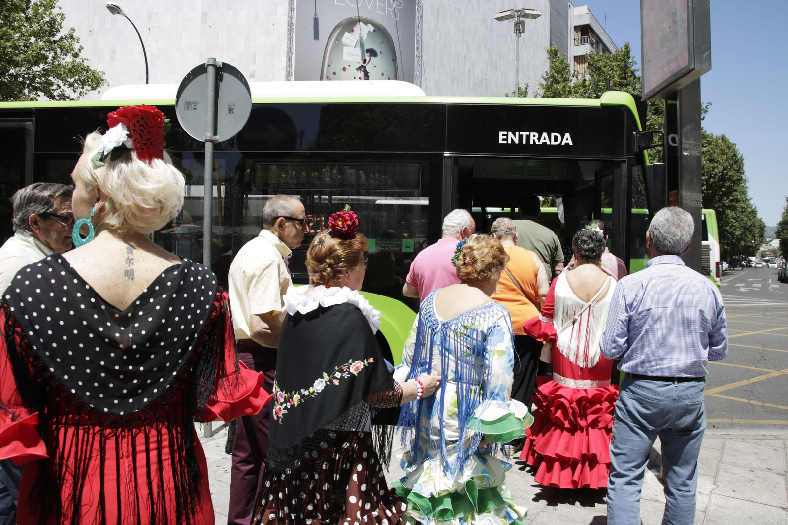 Mujeres con trajes de flamenca se suben a un autobús.