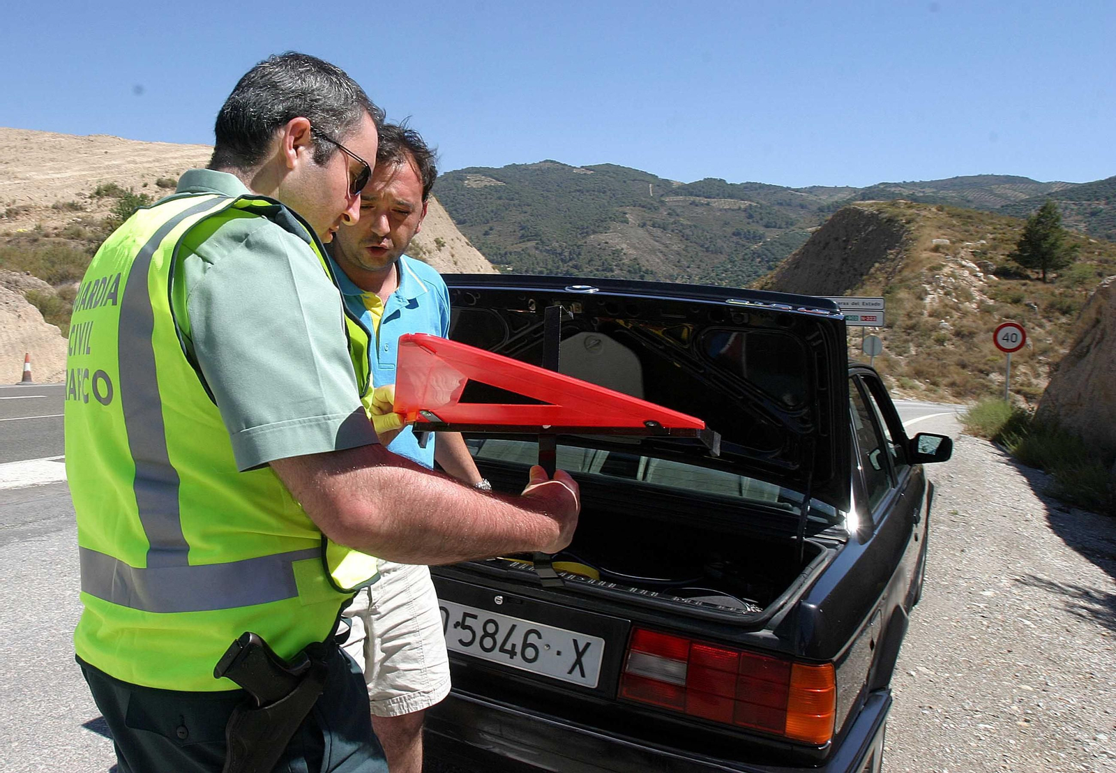 Un Guardia Civil inspecciona un triángulo de emergencias de un vehículo.