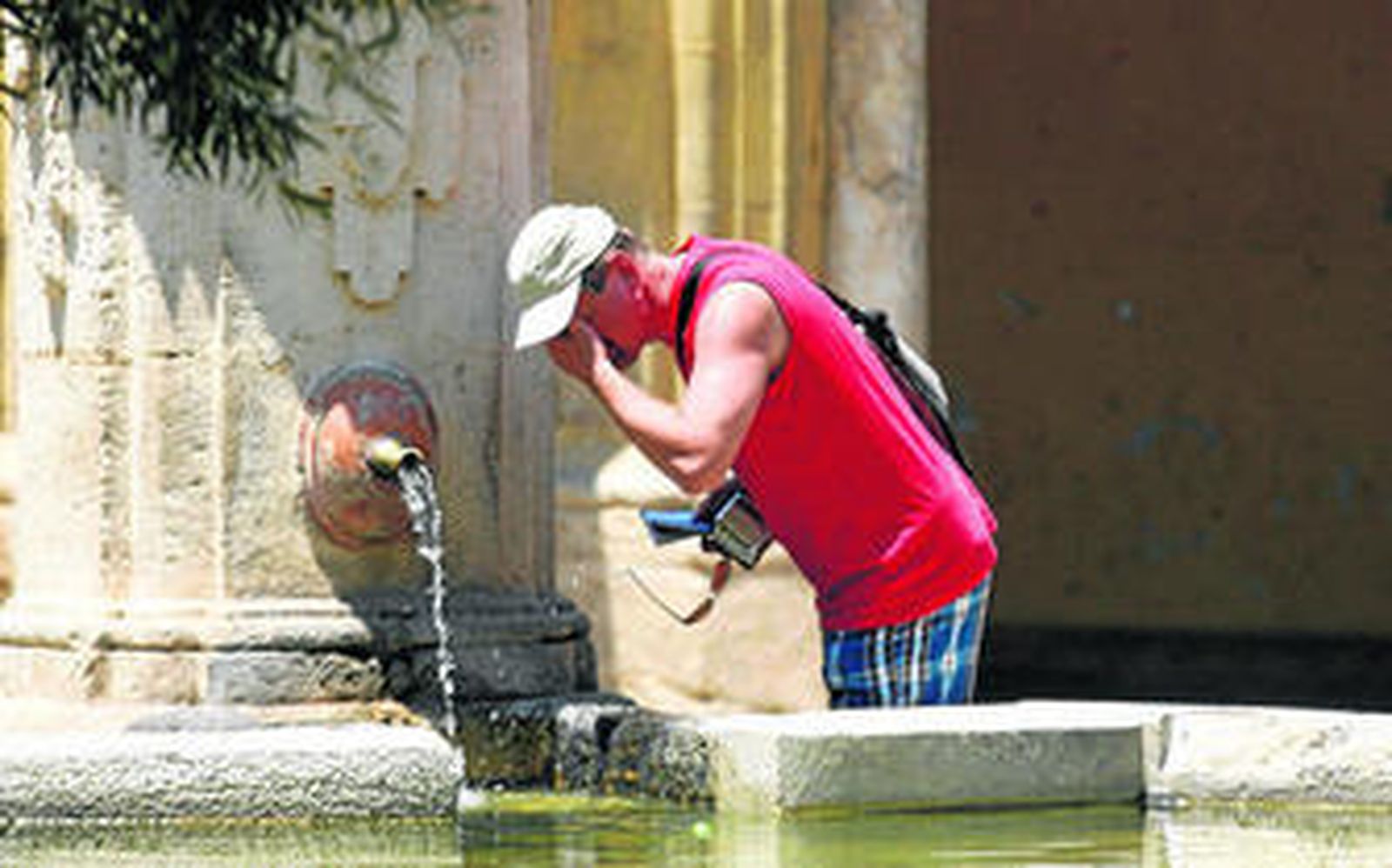 Un turista se refresca del intenso calor, ayer, en una de la fuentes públicas de Córdoba.