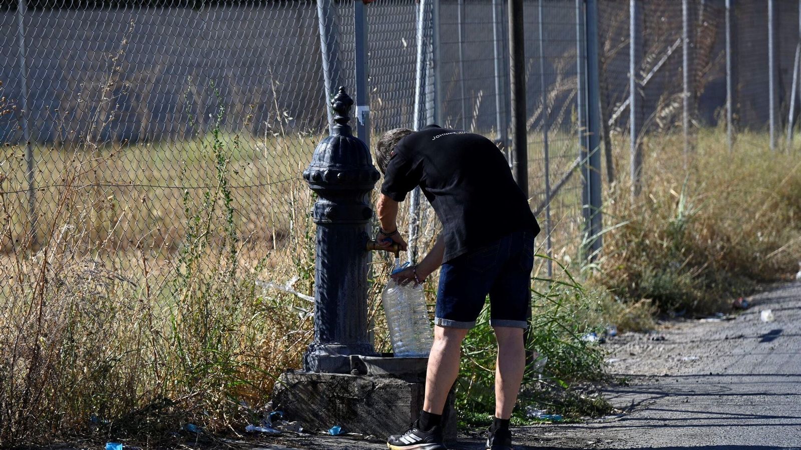 Un hombre llena una garrafa en una fuente en El Alamillo