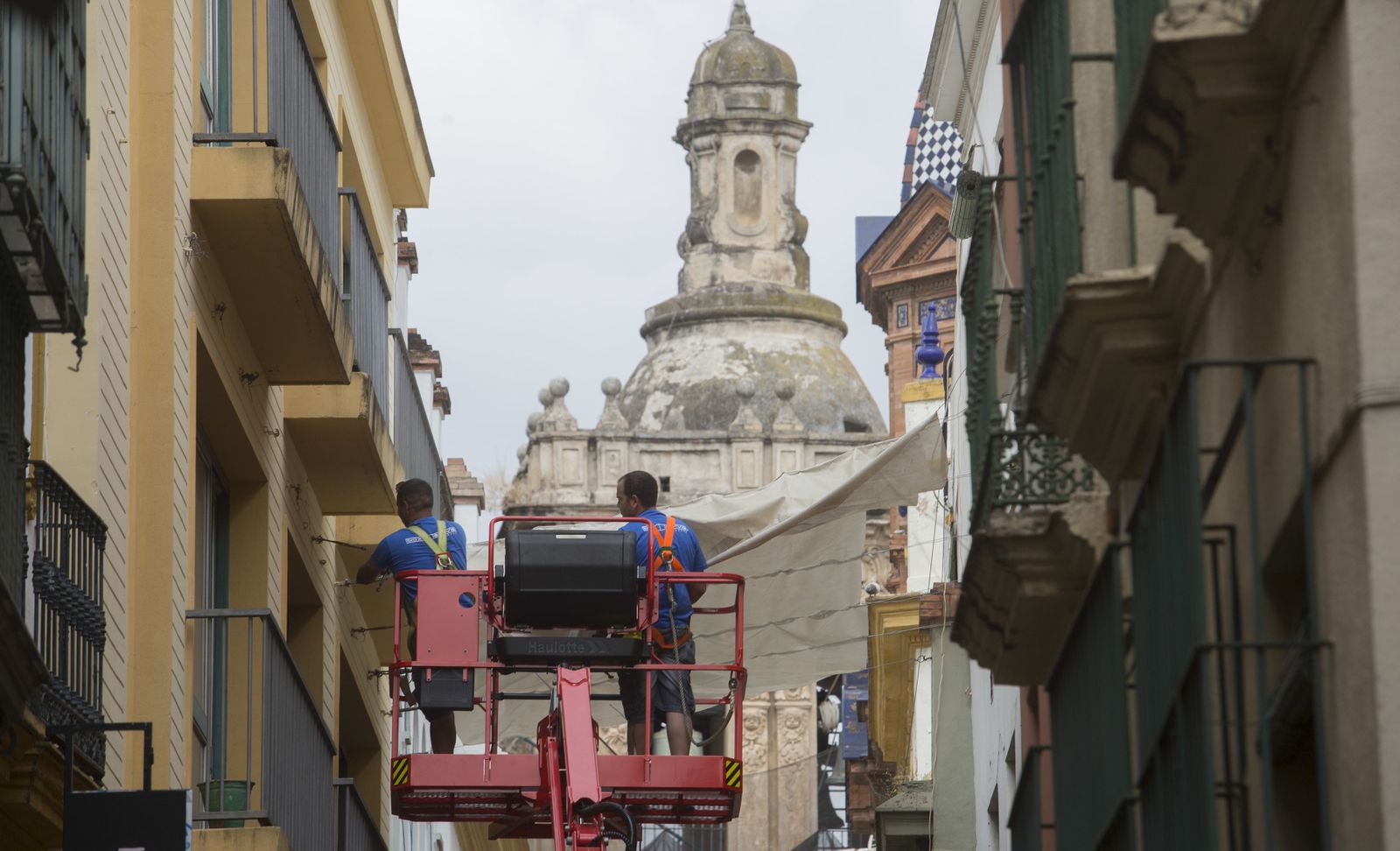 Los operarios instalando las velas en la calle Alcaicería.