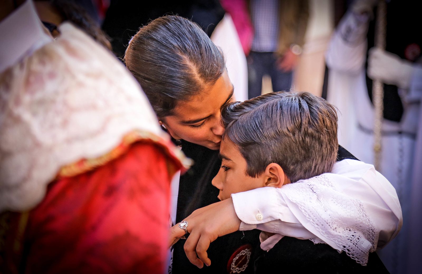 Una monaguilla besa a un monaguillo en uno de los primeros compases de la estación de penitencia de la Hermandad de la Coronación.
