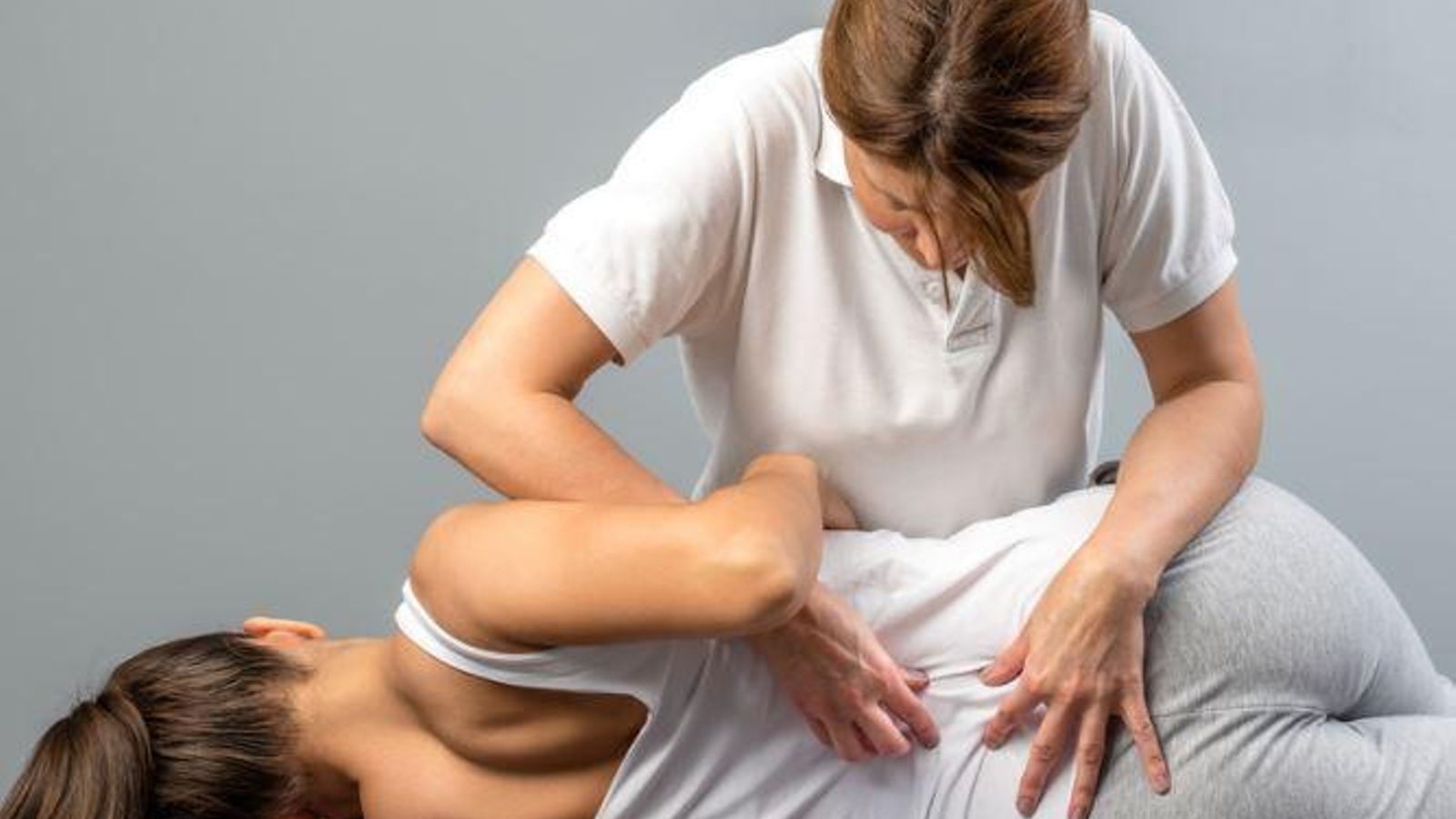 Una fisio revisa la columna vertebral de una paciente.