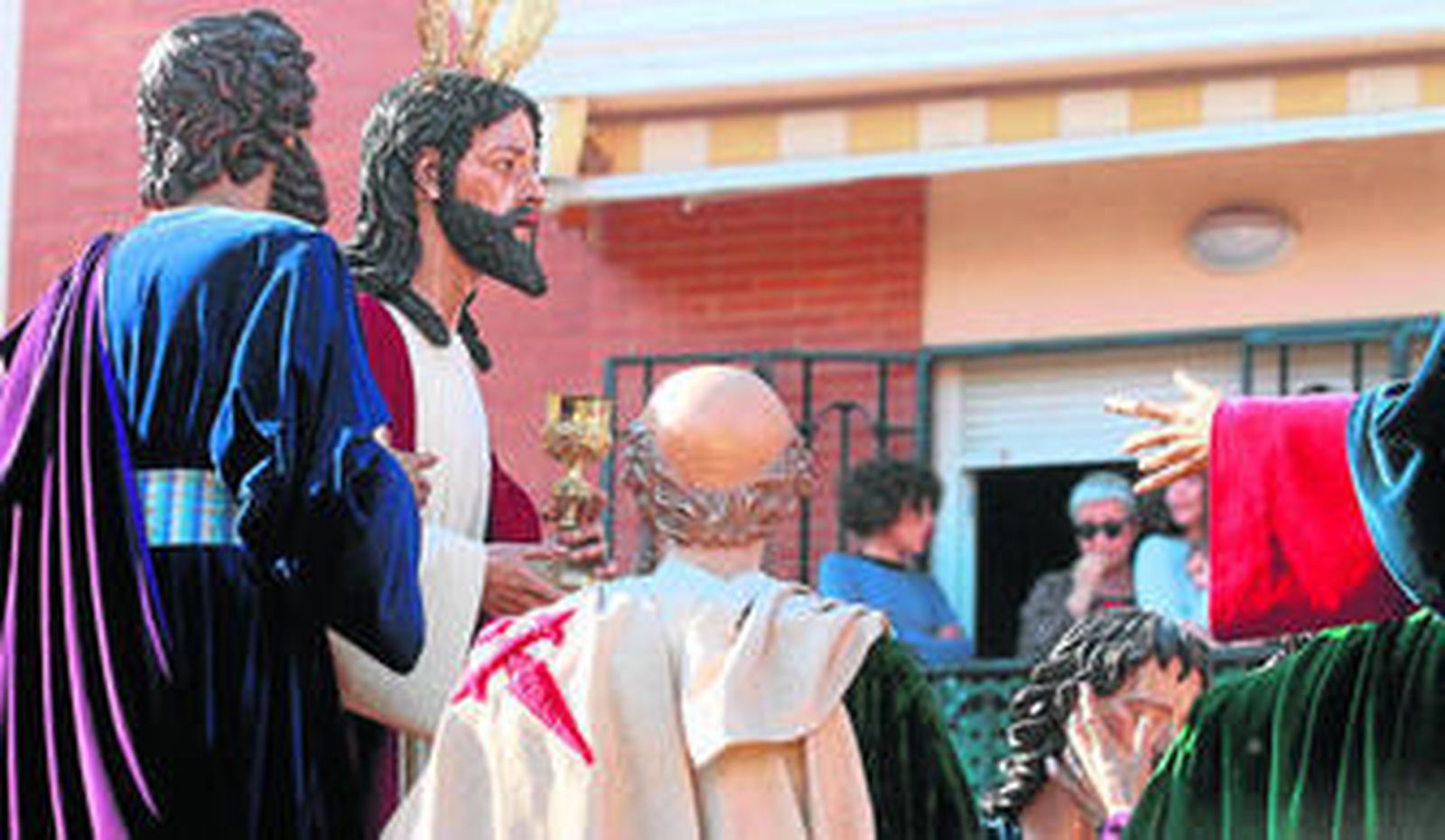El Señor de la Fe en su Sagrada Cena pasa junto a los balcones de su barrio.