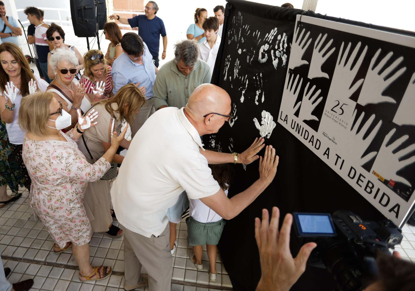 Algunos participantes en el acto del PP estampan sus manos blancos en un mural.