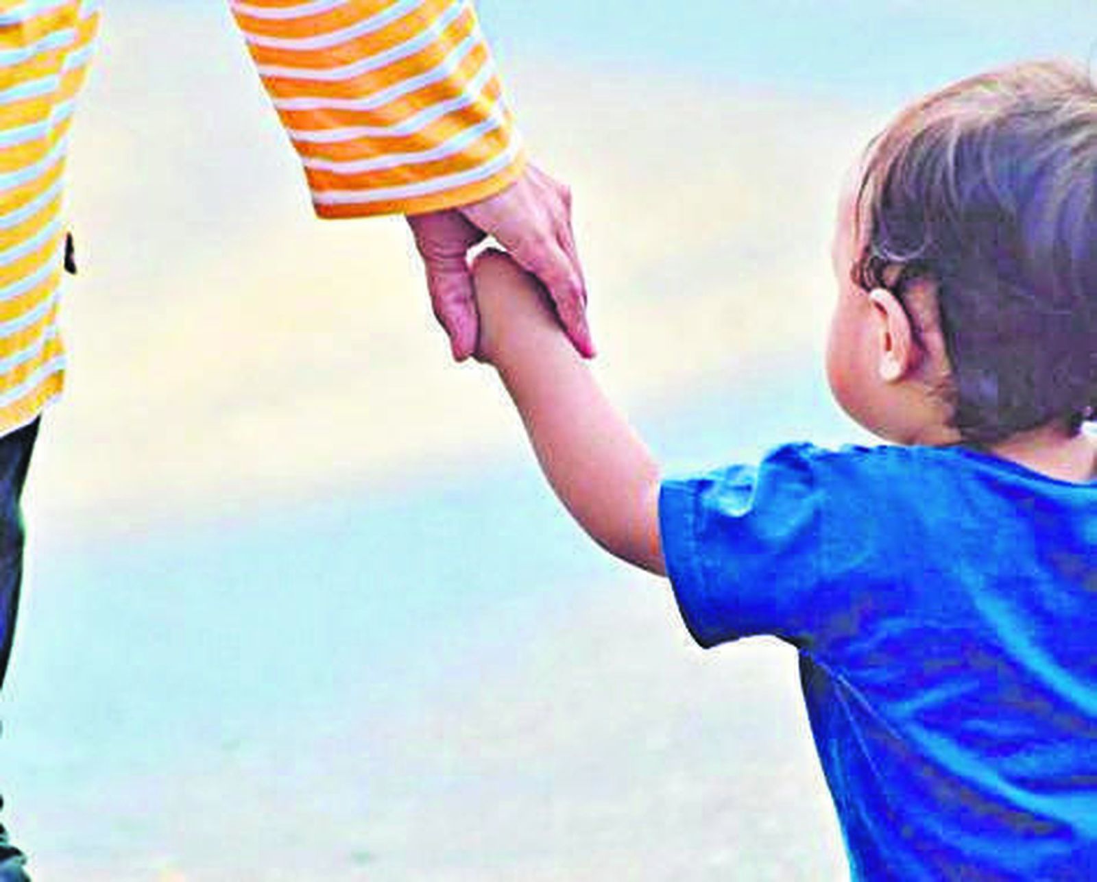 Una mujer le da la mano a un niño pequeño.