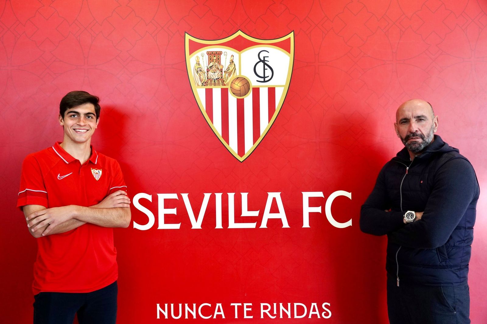 Juanlu posa ante el escudo del Sevilla junto a Monchi.