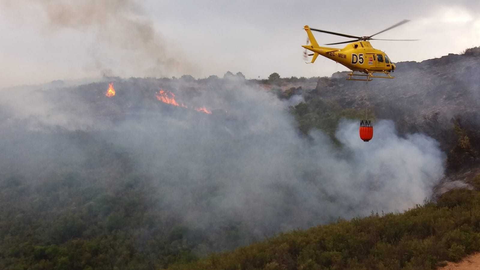 Un helicóptero descarga agua en la zona afectada por el fuego.