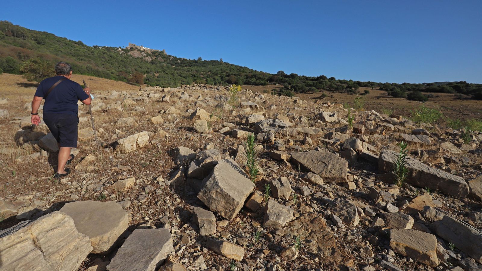 Un senderista pasea por la desértica orilla del embalse de Guadarranque