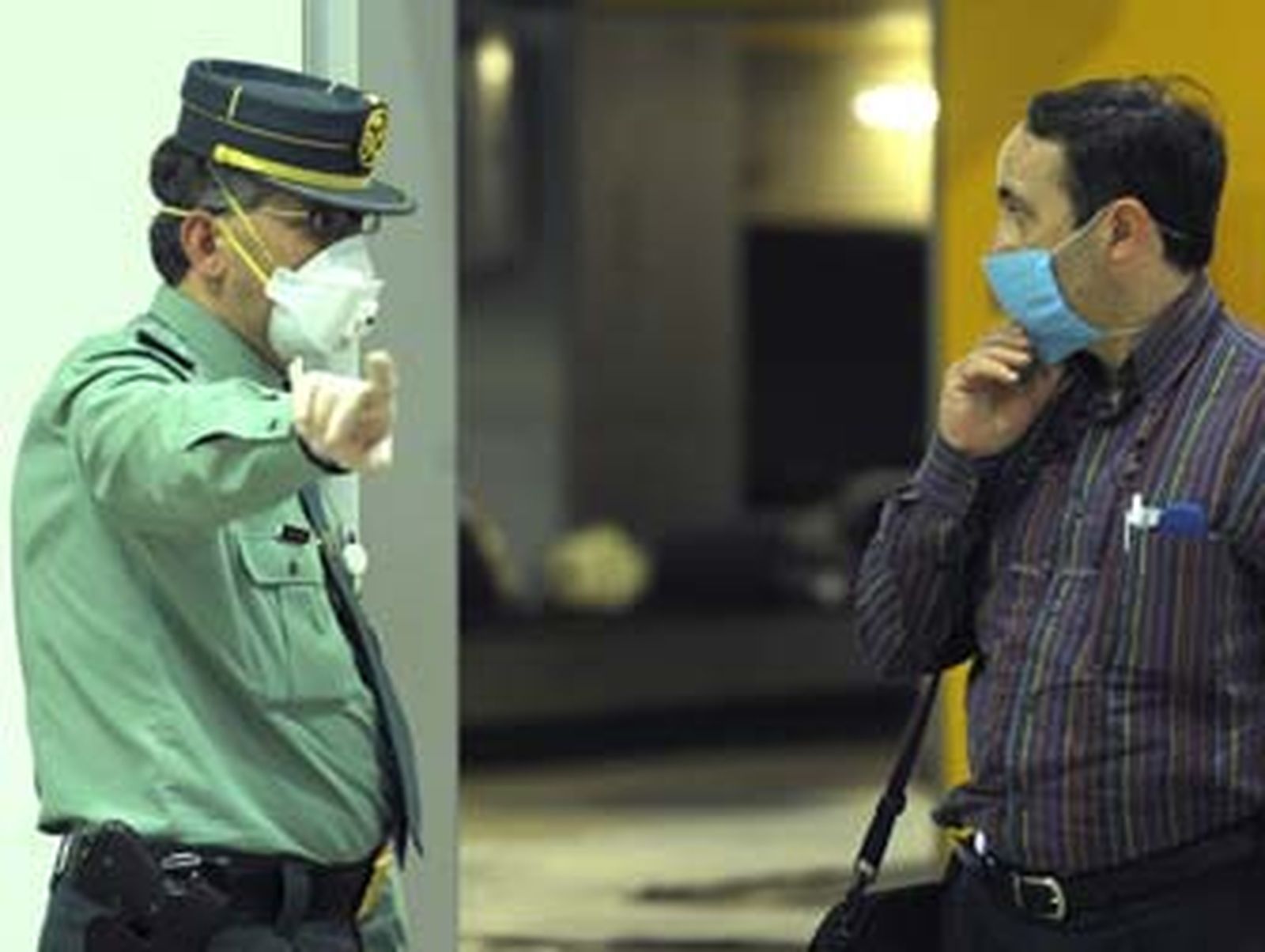 Un agente de la Guardia Civil hace indicaciones a un viajero en un aeropuerto.