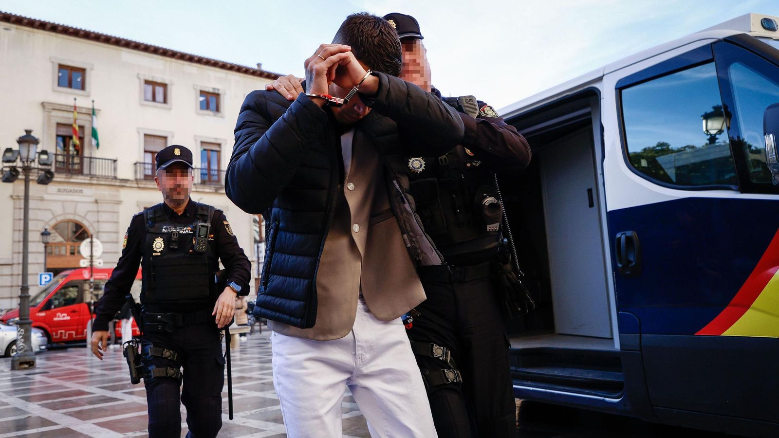 Uno de los acusados se tapa la cara a su entrada a los juzgados.