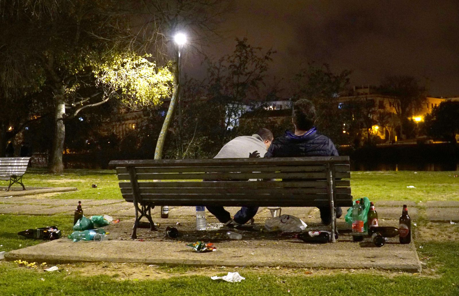 Dos jóvenes bebiendo en un parque.