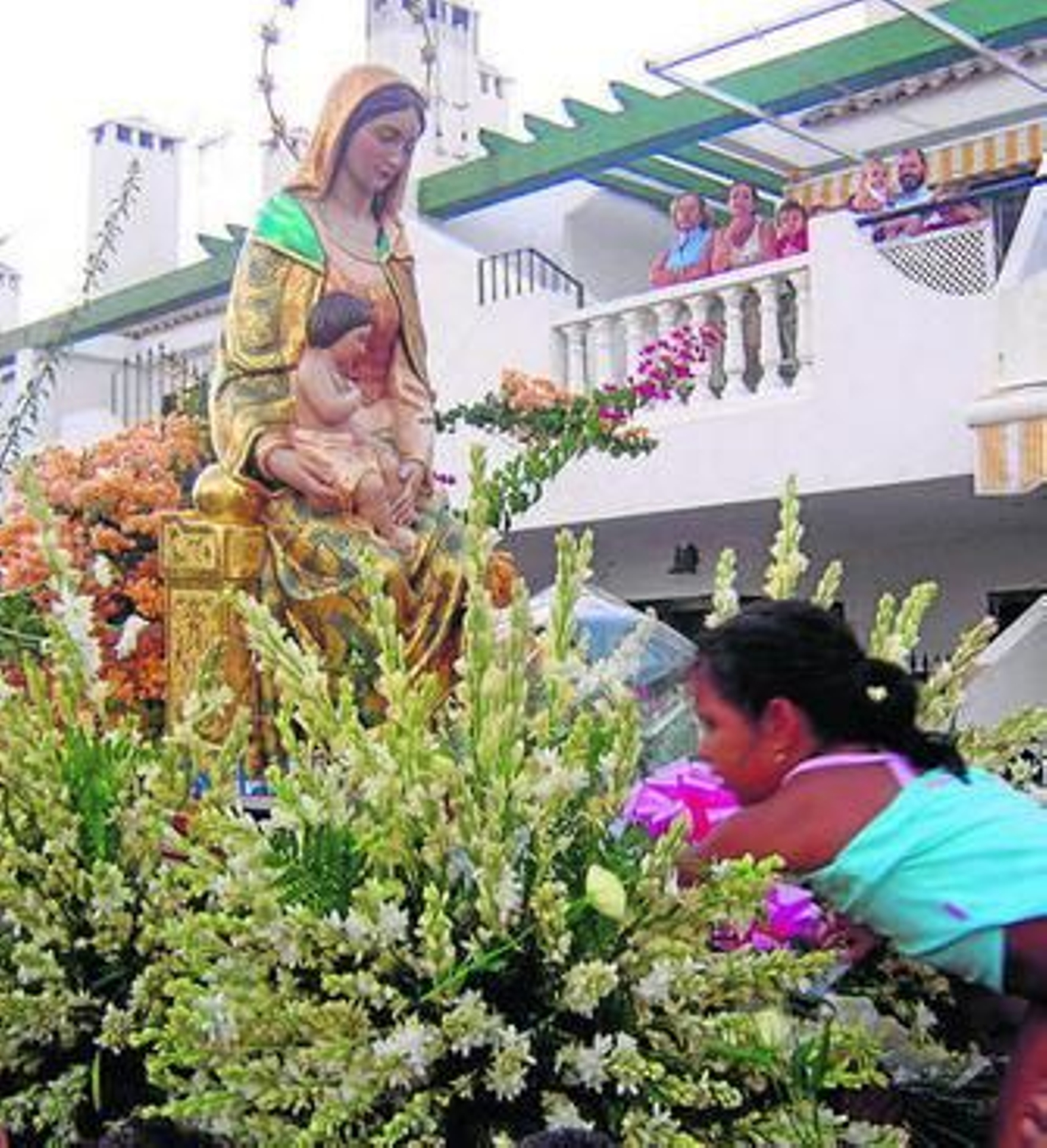 Una niña realiza una ofrenda de flores a la imagen.