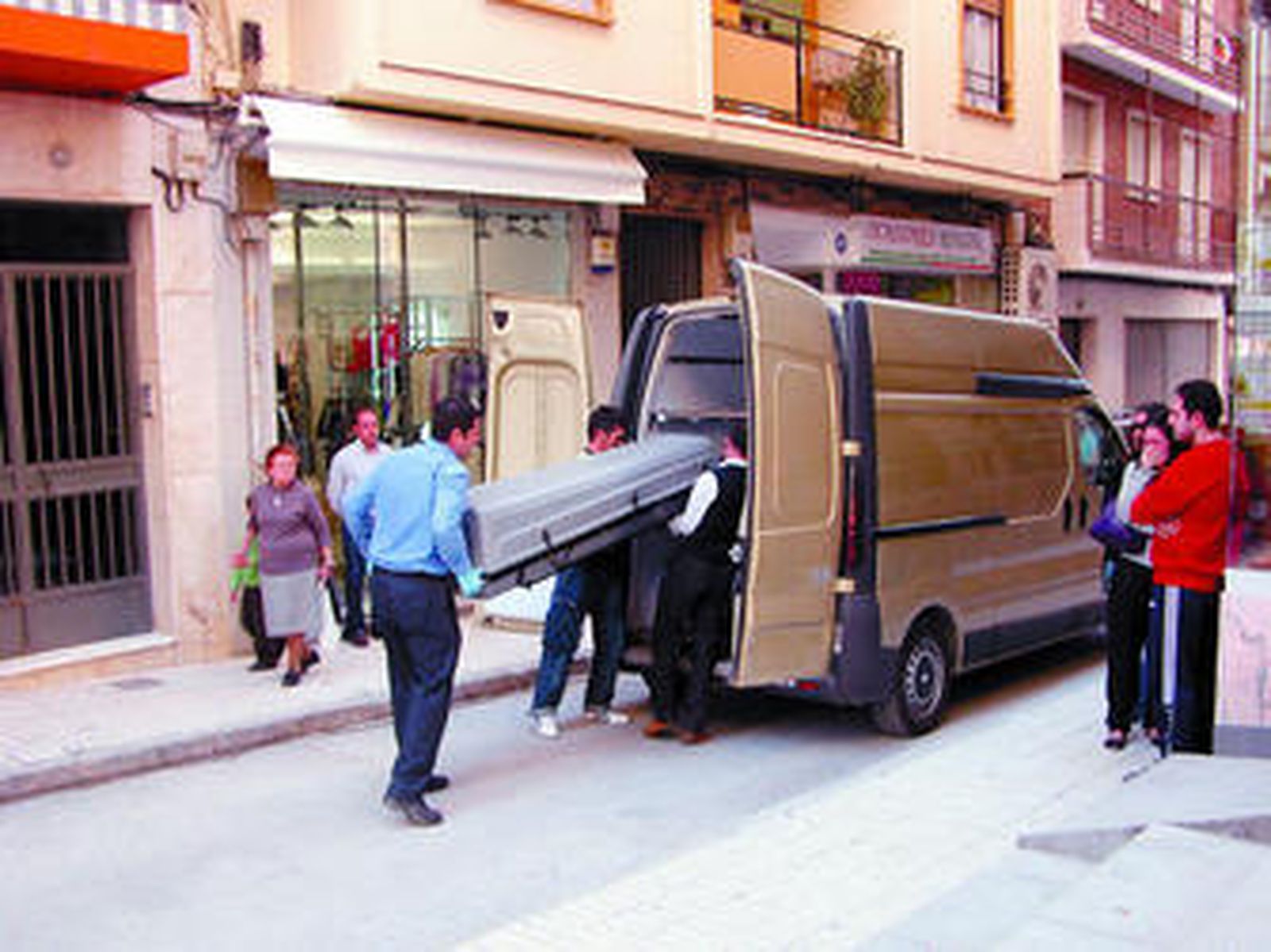 El cuerpo de la víctima es trasladado por varios operarios al Instituto Anatómico Forense en presencia de una familiar que llora.