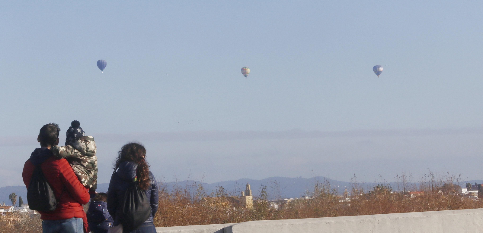 Una familia observa el paso de los globos de los Reyes Magos por Córdoba.