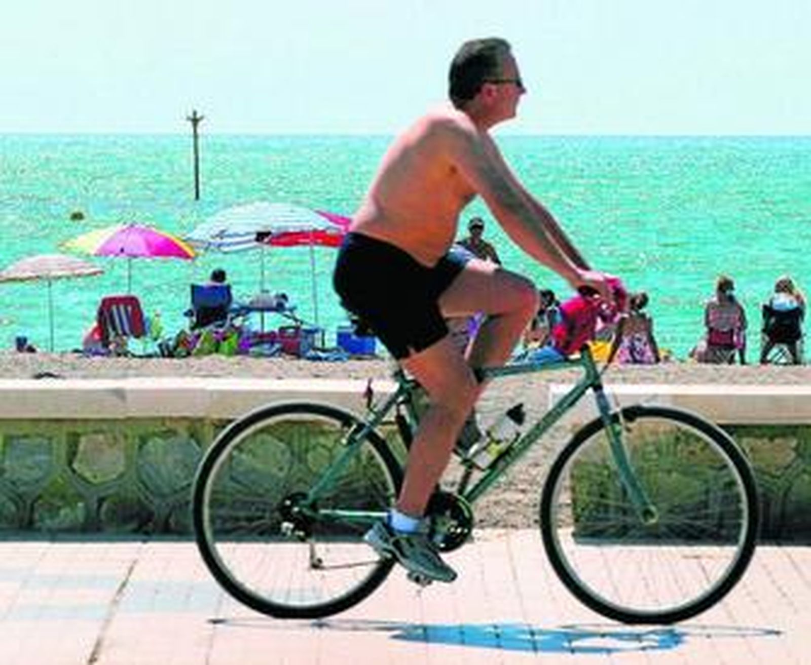 Un hombre pasea en bicicleta por el paseo marítimo Antonio Machado.