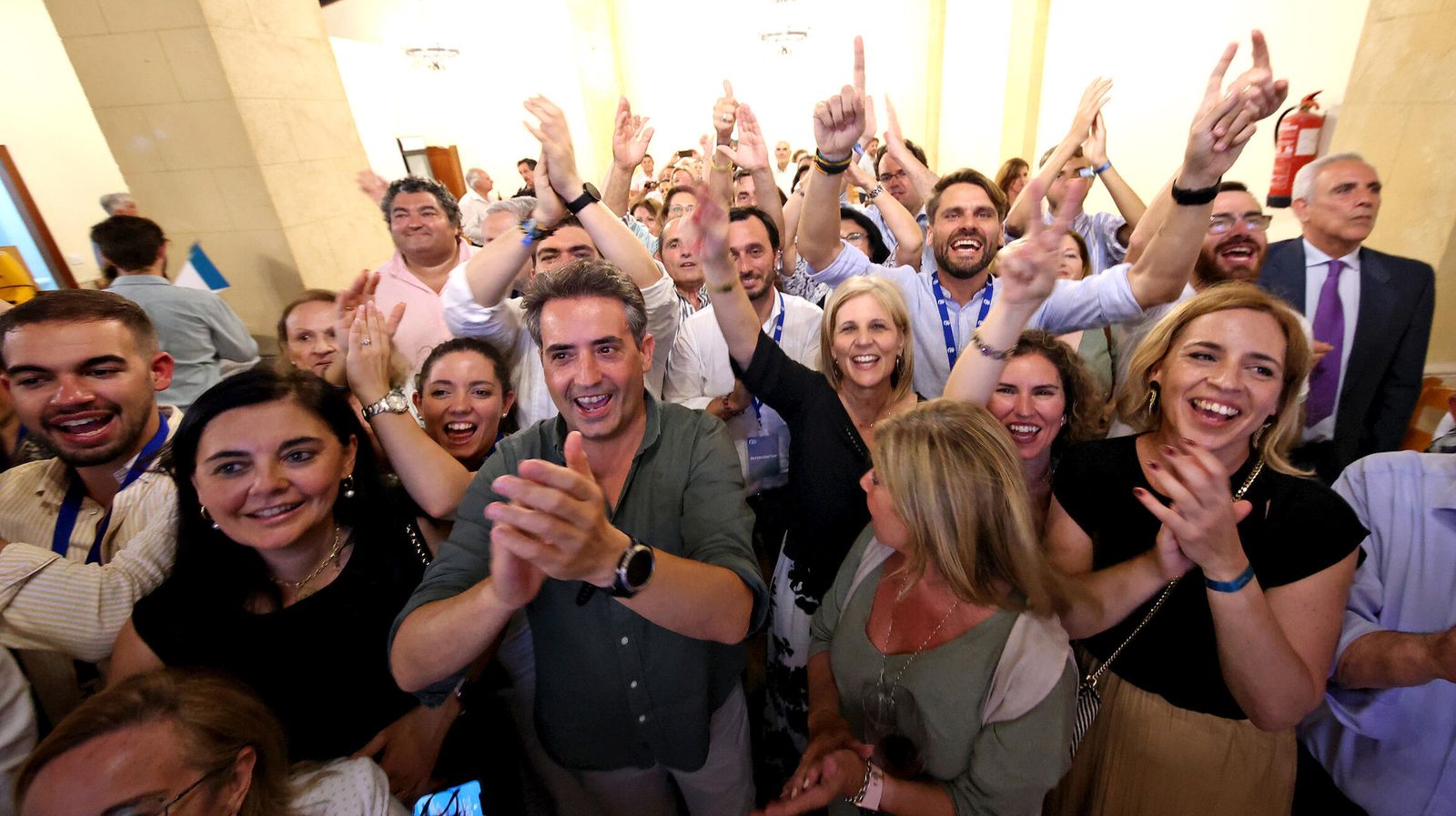 Antonio Saldaña y otros miembros y simpatizantes del PP, aplaudiendo la comparecencia de Juanma Moreno el domingo por la noche.