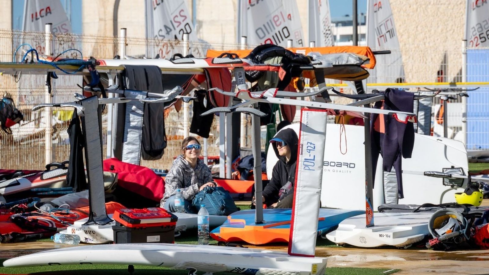 Dos participantes esperan en la costa el posible comienzo de la jornada