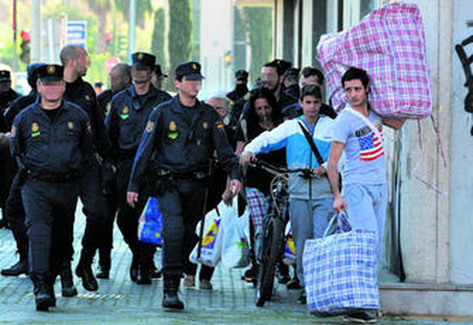 Varios inquilinos dejan la Corrala Utopía cargados con sus enseres y acompañados por la Policía.