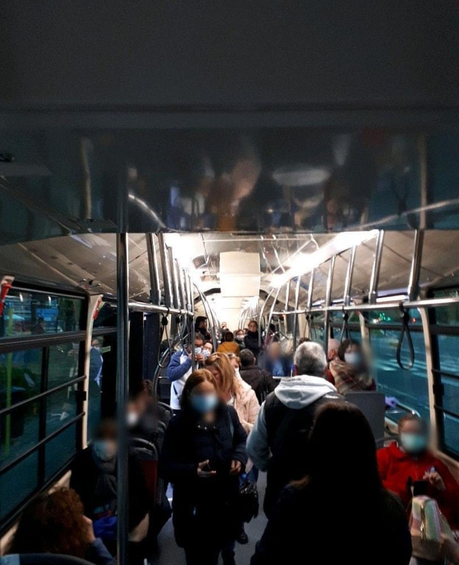 Interior de un autobús de Tussam repleto de usuarios, algunos con mascarillas.