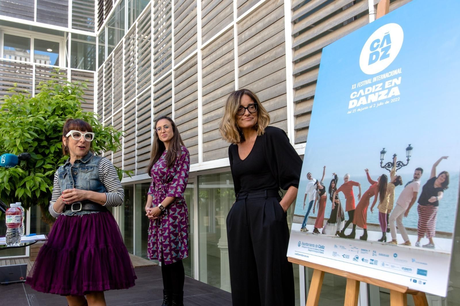 Las concejalas Monte Mures y Lola Cazalilla y la directora del Cádiz en Danza, Lorena Benot, junto al cartel del XX Cádiz en Danza.