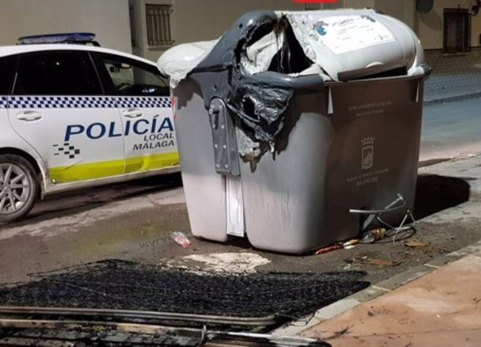 Imagen de archivo de un coche de la Policía Local de Málaga junto a un contenedor de basura.