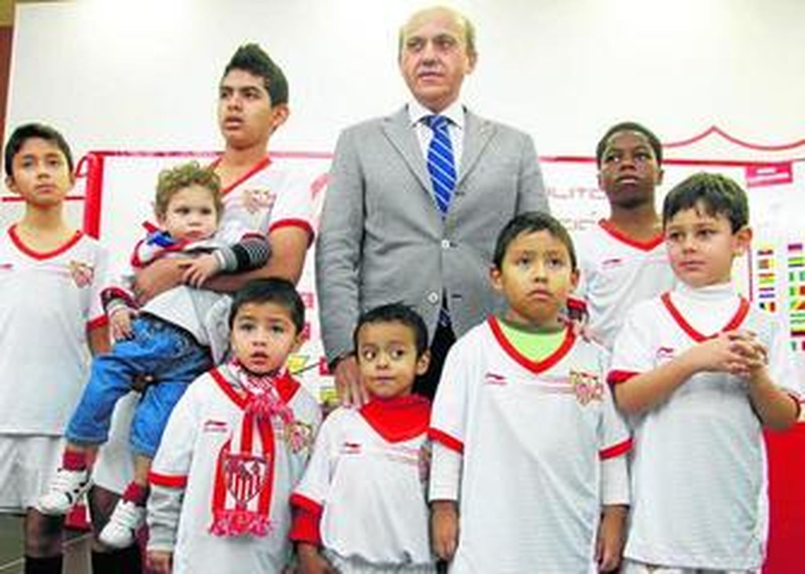 Del Nido, con niños de varios continentes equipados con el uniforme europeo del Sevilla.