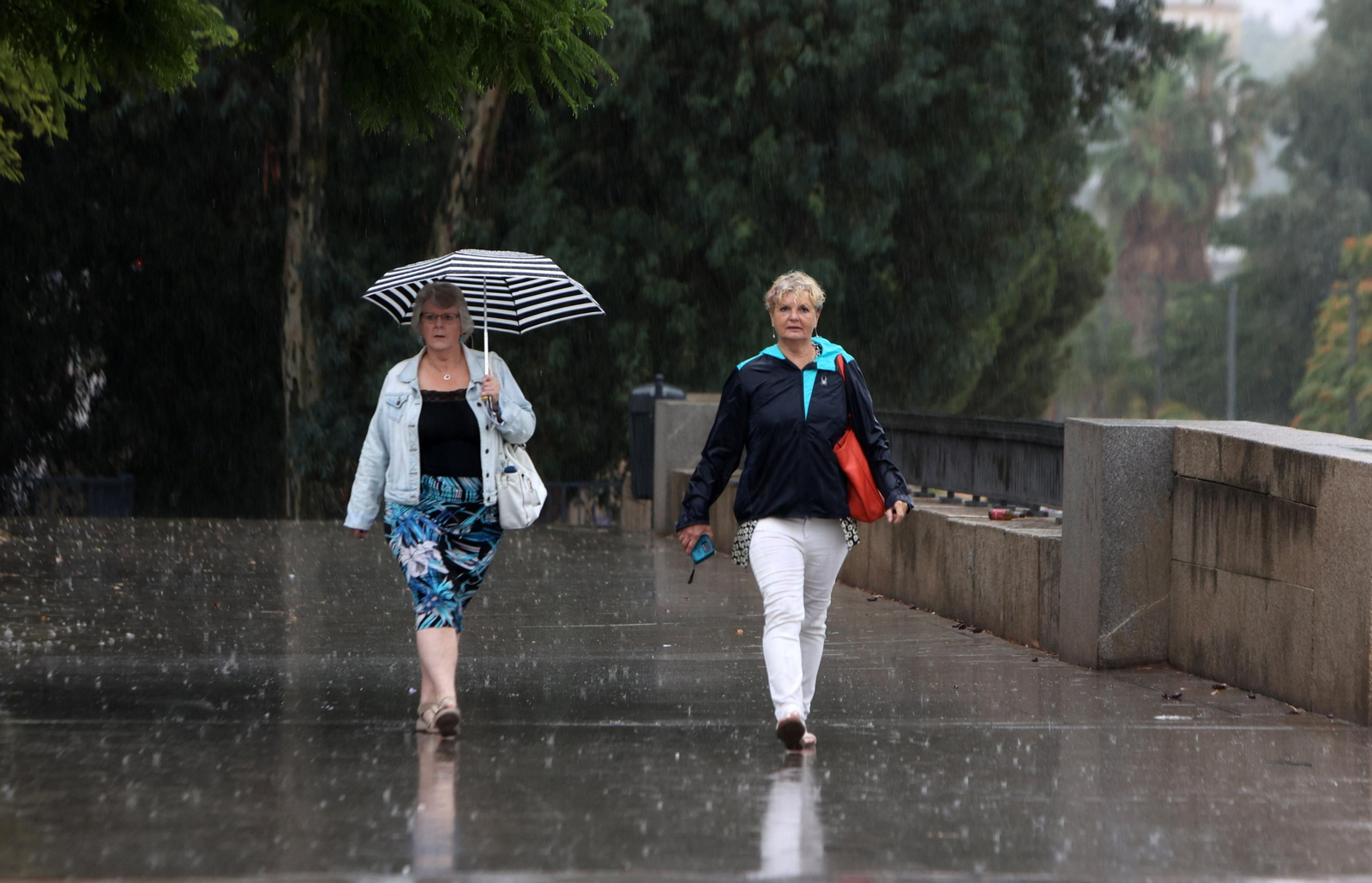 Dos turistas pasean por el centro de la ciudad en plena tormenta.