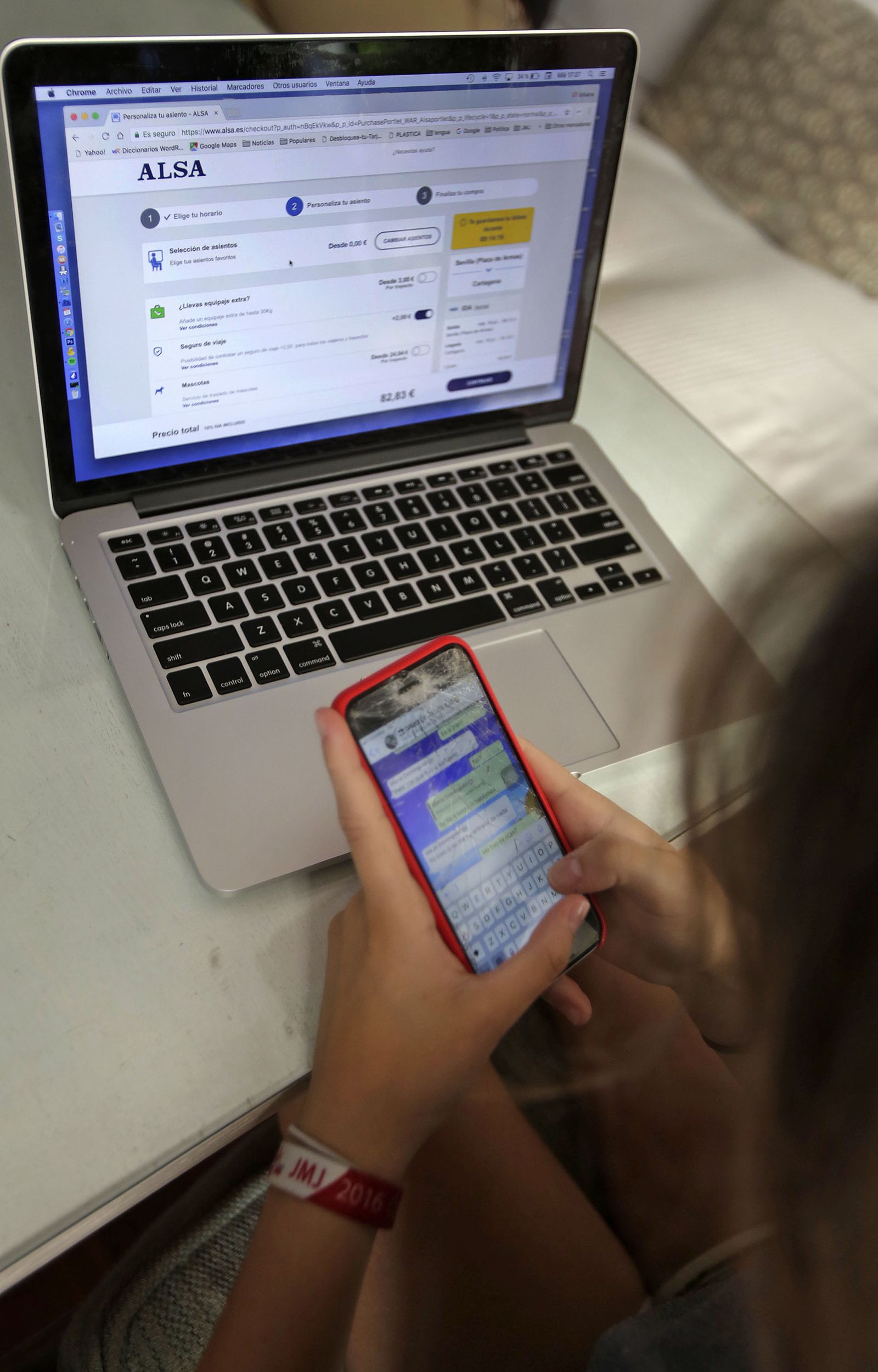 Una usuaria utilizando su móvil junto a un ordenador.