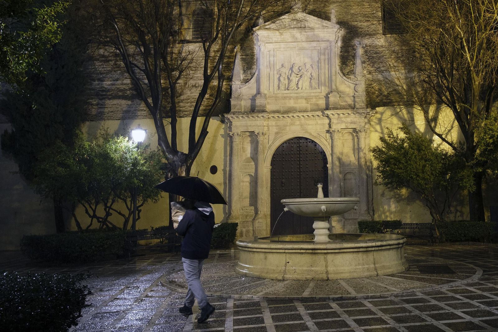 Un hombre camina con un paraguas por el centro de Sevilla