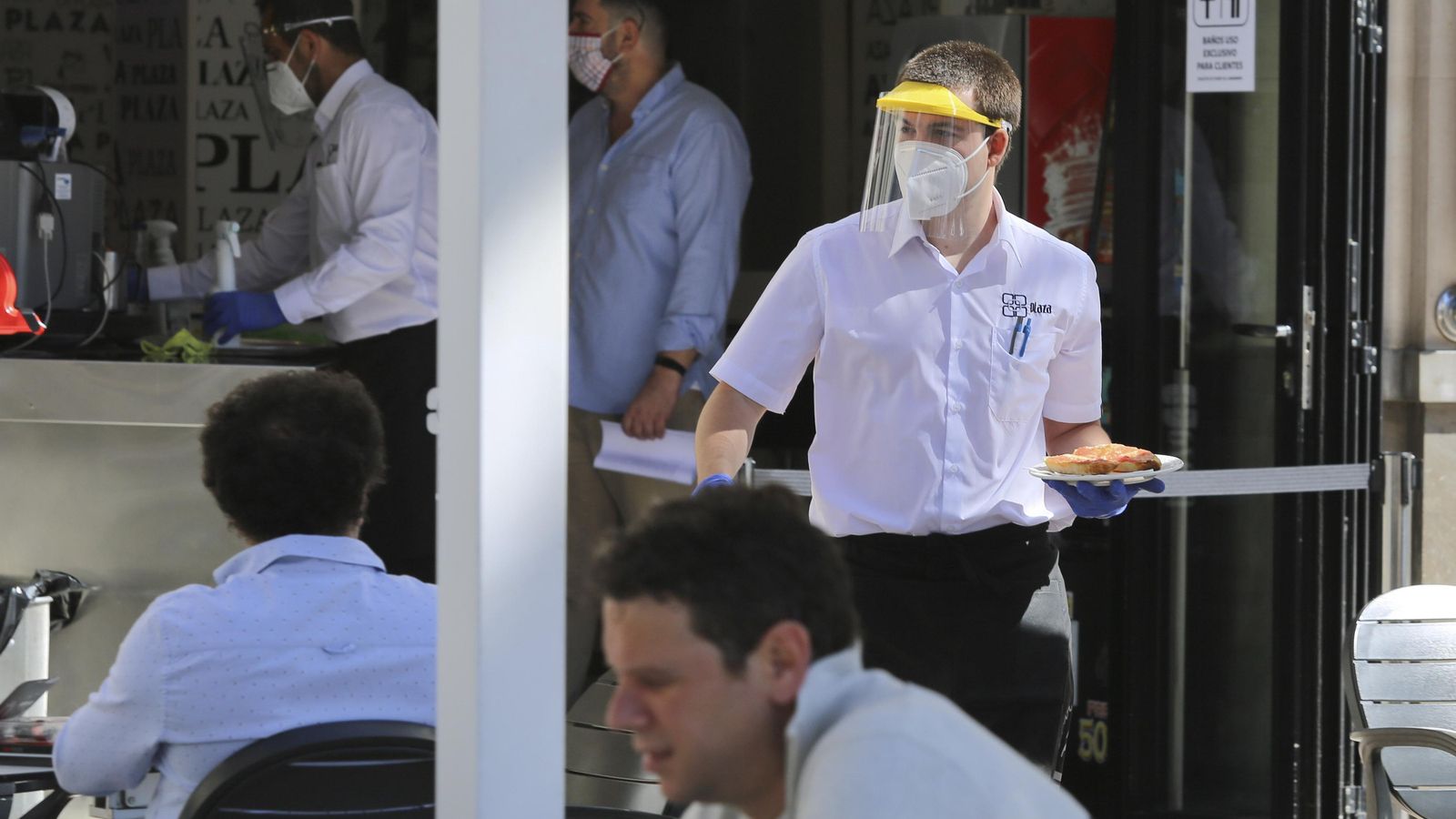 Un camarero se dirige a la terraza para servir a los clientes.
