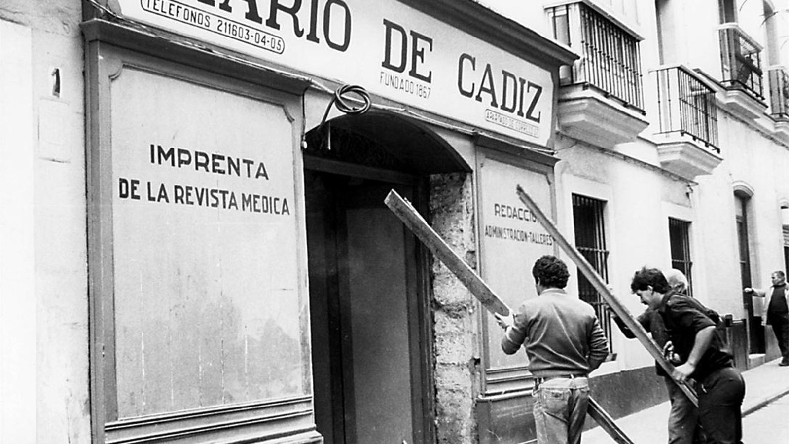 Foto antigua de Juan Torres y su equipo arreglando la portada de la antigua sede de Diario de Cádiz