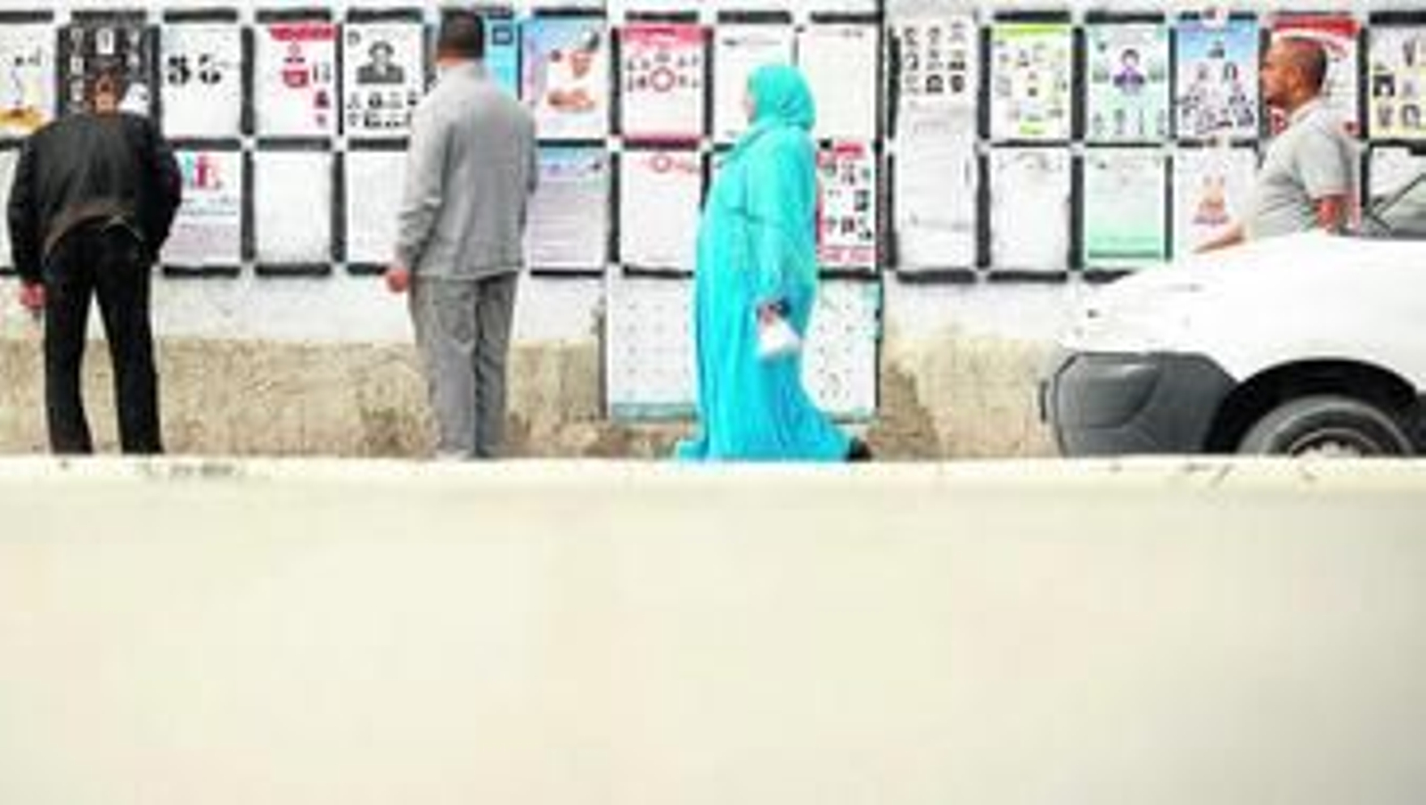 Votantes tunecinos contemplan en un muro la propaganda electoral de los distintos candidatos en los comicios de hoy.