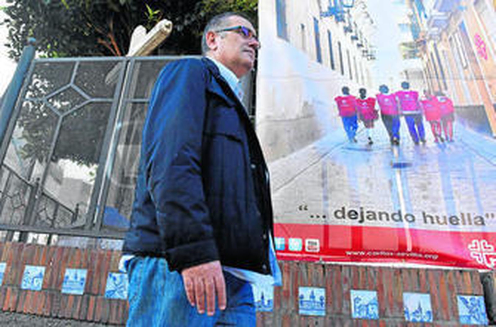 Aurelio Domínguez, ayer por la calle San Jacinto junto a un cartel de Cáritas.