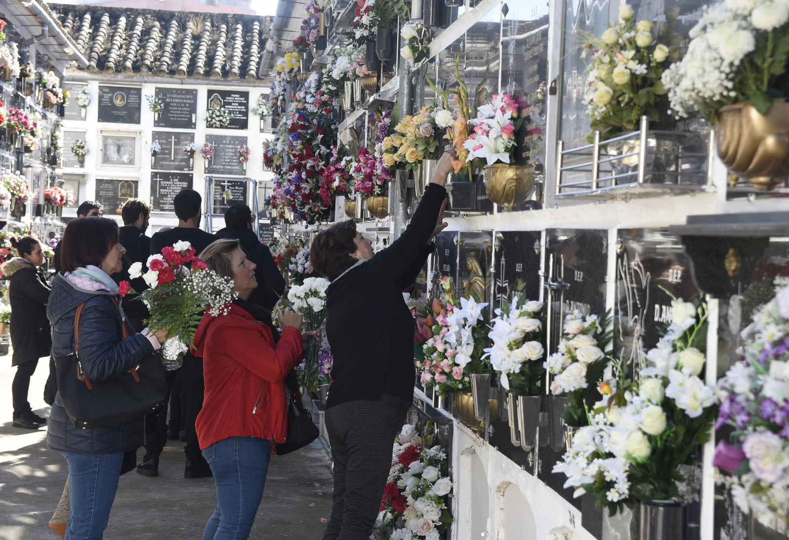 Una mujer coloca flores en un nicho en el cementerio de San Rafael.