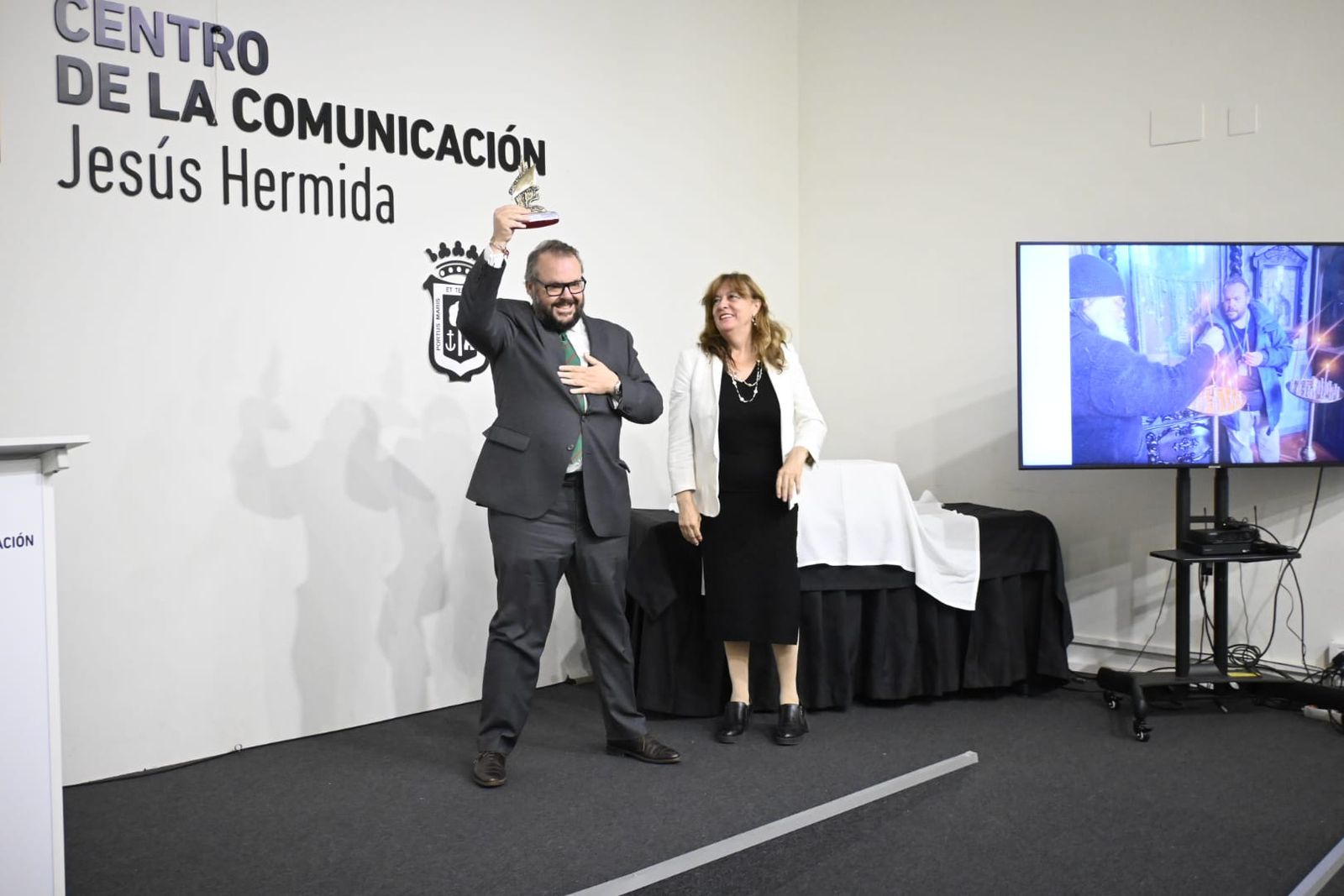 El periodista Luis de Vega alza el premio Ángel Serradilla en señal de agradecimiento, durante la entrega del galardón en el Centro de la Comunicación Jesús Hermida.