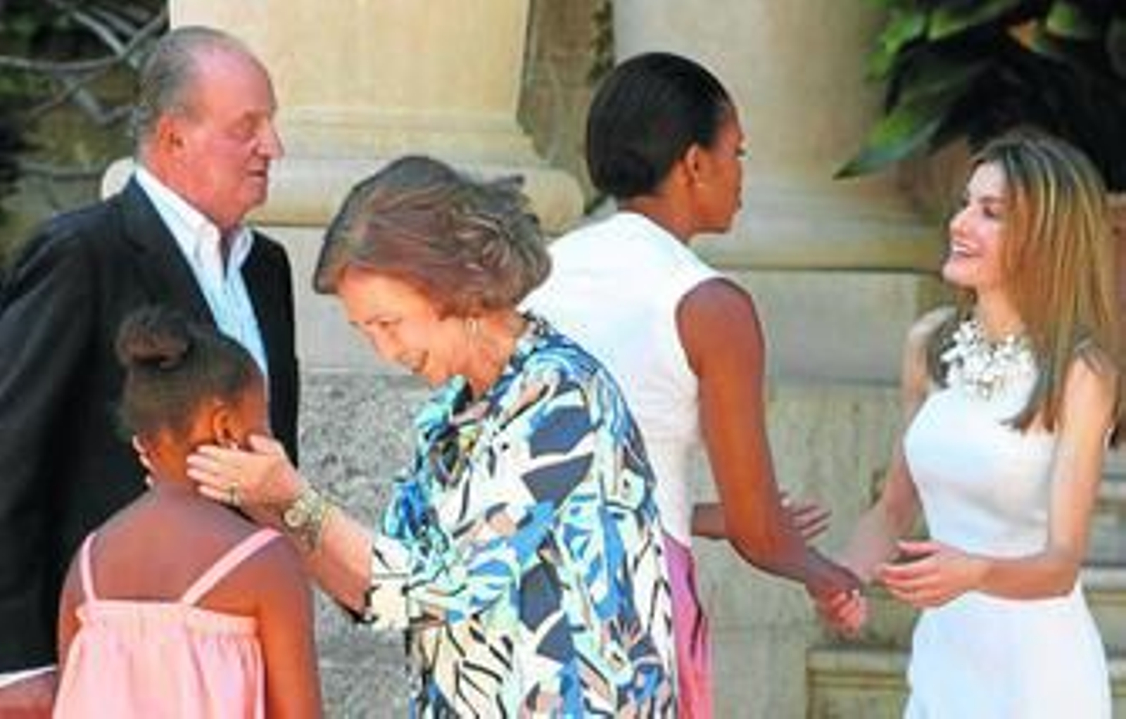 La Reina saluda a Sasha en presencia del Rey, mientras Michelle Obama dialoga con doña Letizia.
