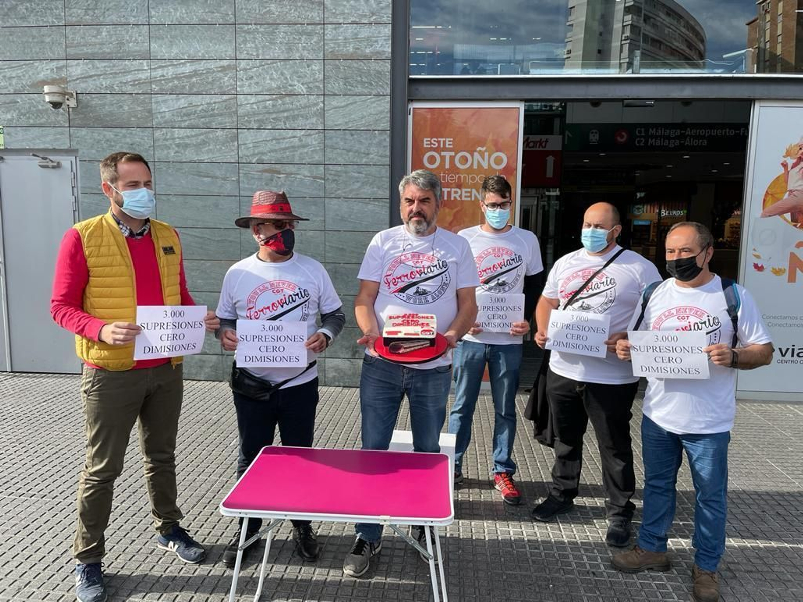Miembros de CGT posan con la tarta que conmemora las 3.000 supresiones en el Cercanías.