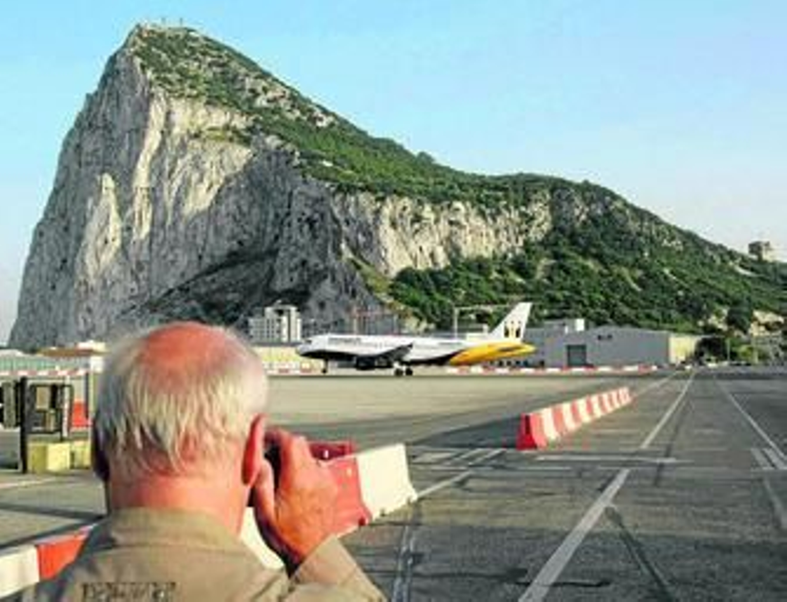 Un hombre hace una foto, ayer, del aterrizaje de un avión en el aeropuerto de Gibraltar.