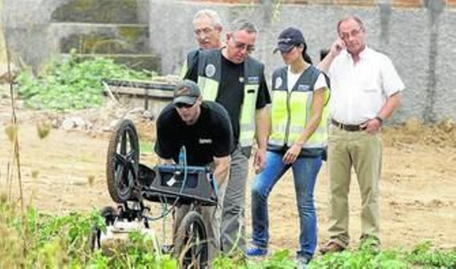 Luis Avial, en el centro con un chaleco de la Policía, observa a su auxiliar manipular el georradar.